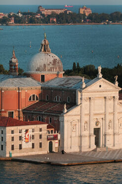 A photo of two priests walking side-by-side in front of a venetian building in Venice, Italy. Artistic framed photograph taken by Photographer Scott Allen Wilson