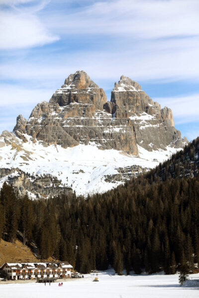 Beautiful landscape photography of the tall Dolomites mountain range in Italy with a forest and houses below, taken by Photographer Scott Allen Wilson.