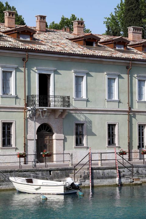 Relaxing photo of a traditional building at the edge of the water taken in Peschiera del Garda, Italy by Photographer Scott Allen Wilson.