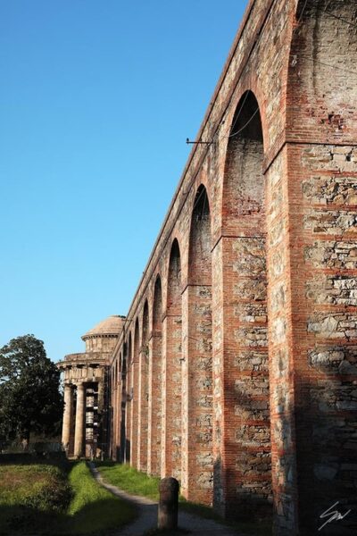 Red brick columns and archs leading to a church in the city of Lucca, Italy. By Photographer Scott Allen Wilson.
