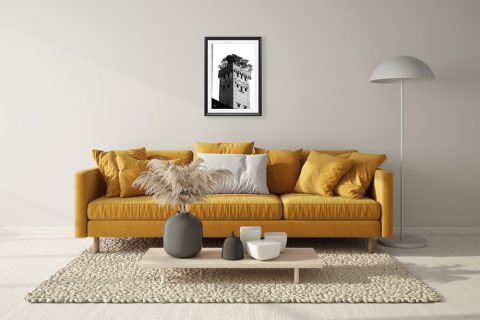 A b&w framed print of Torre Guinigi with trees on top of it in Lucca, Italy, hanging in a minimal living room. By Photographer Scott Allen Wilson.