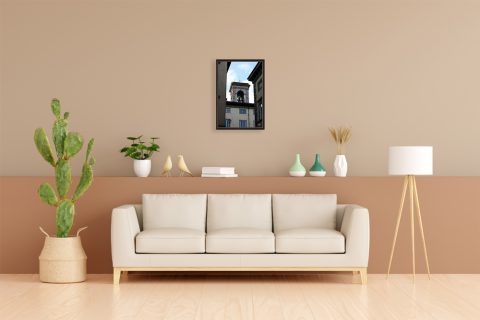 A dark brown framed print of a bell tower in Lucca, Italy, hanging in a cream toned living room. By Photographer Scott Allen Wilson.