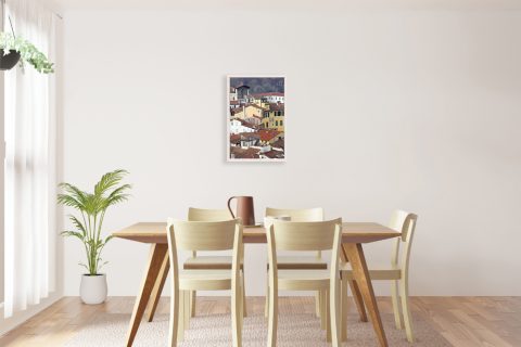 A white framed print of a view of Lucca, Italy, hanging in a minimal kitchen with wooden furniture. By Photographer Scott Allen Wilson.