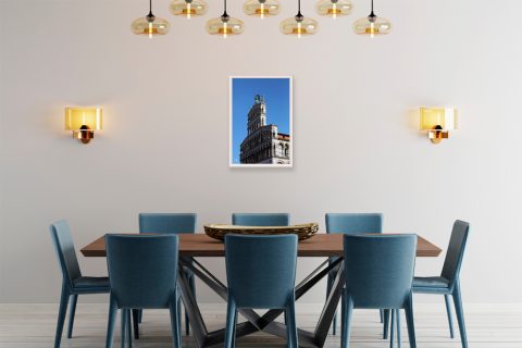 A white framed print of Church of San Michele in Foro in Lucca, Italy, hanging in a modern kitchen with blue furniture. By Photographer Scott Allen Wilson.