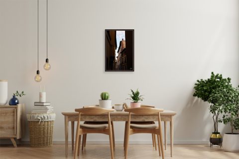 A dark brown framed print of rooftops in Lucca, Italy, hanging in a minimal kitchen with wooden decor. By Photographer Scott Allen Wilson.
