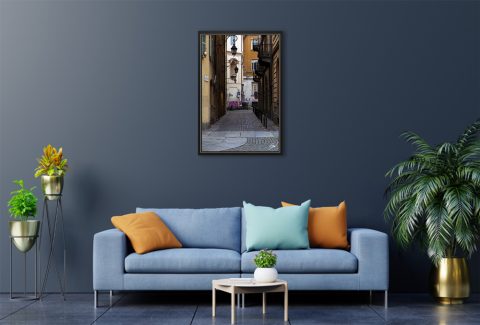A black framed print of a cobblestone street in Torino, Italy, hanging in a modern living room. By Photographer Scott Allen Wilson.