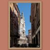 Ciao Cremona by Scott Allen Wilson – fine art print of a narrow Italian street leading to the ornate facade and spire of Cremona Cathedral under a clear blue sky, displayed in a natural wood frame on a terracotta background