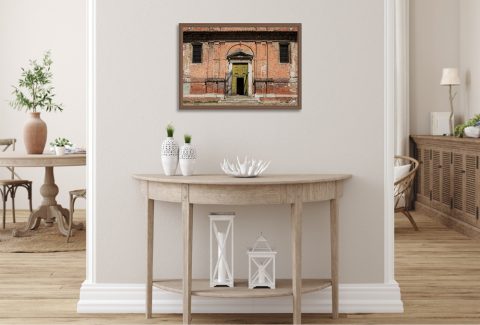 The Door Is Always Greener by Scott Allen Wilson framed travel print displayed on a hallway wall above a wooden console table.