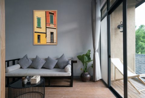 The Colors of Cremona by Scott Allen Wilson framed travel print displayed on a living room wall above a grey sofa.