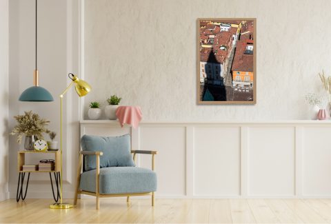 The Inevitable by Scott Allen Wilson framed travel print displayed on a living room wall beside a blue armchair.