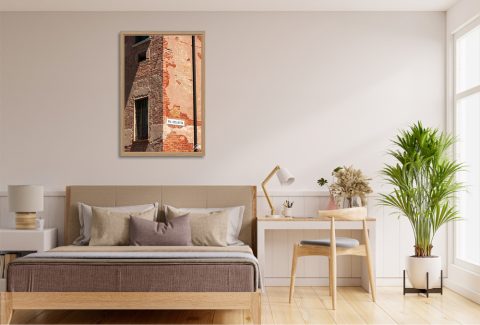 Vai Via Colletta by Scott Allen Wilson framed travel print displayed on a bedroom wall above a wooden bed frame.