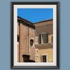Fine art framed print of contrasting historic brick and warm yellow stucco facades with shuttered windows against a deep blue sky, Wait A Minute by Scott Allen Wilson, available in 8x12 and 16x24.