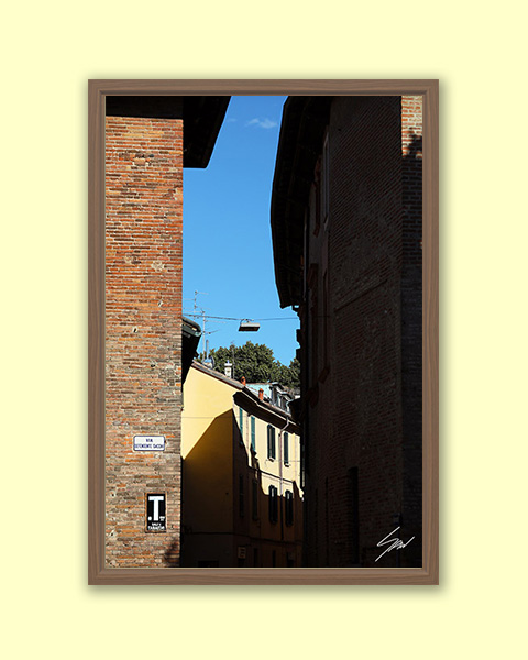 Fine art travel photograph of light and shadow between historic buildings in Pavia.