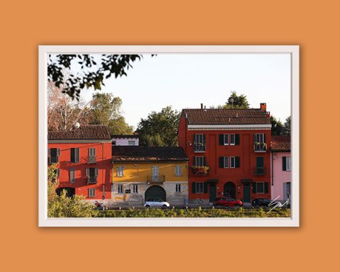 Travel framed print of colorful Italian buildings displayed in a modern living room interior.