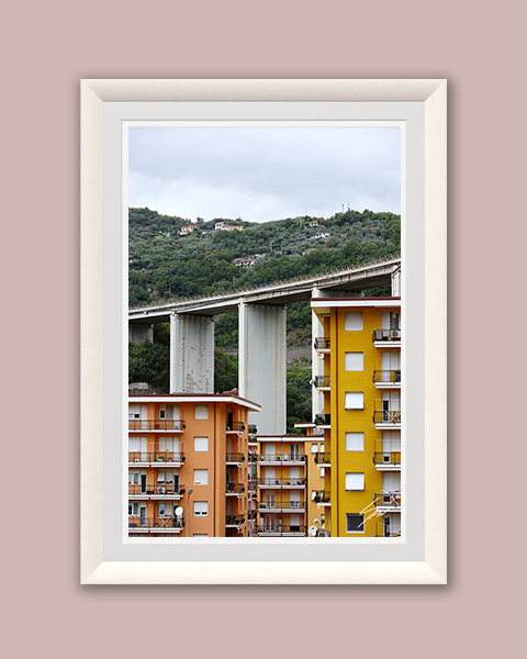 Fine art photograph of vibrant apartment buildings framed by a sweeping concrete viaduct on the Italian Riviera.