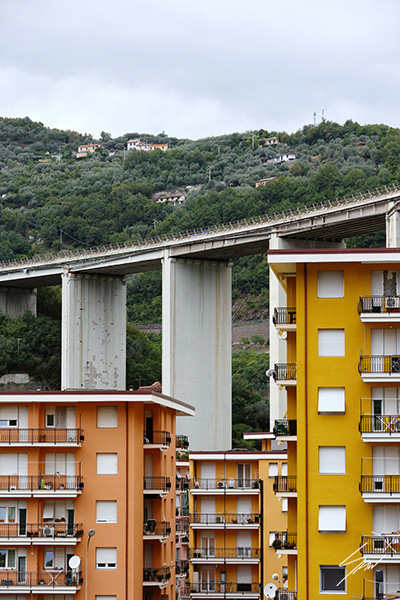 Fine art photograph of vibrant apartment buildings framed by a sweeping concrete viaduct on the Italian Riviera.