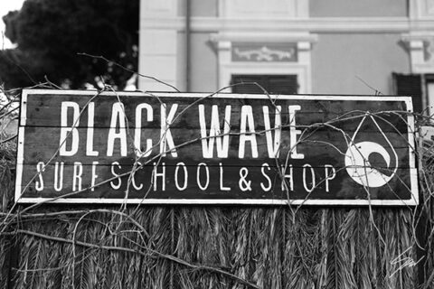 Travel fine art print featuring the Black Wave Surf School sign in monochrome, celebrating surf culture and the charm of the Italian coast.