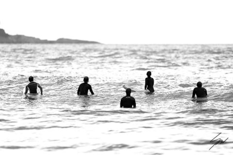 Black and white fine art photograph of five surfers waiting beyond the breaking waves on the Mediterranean Sea.