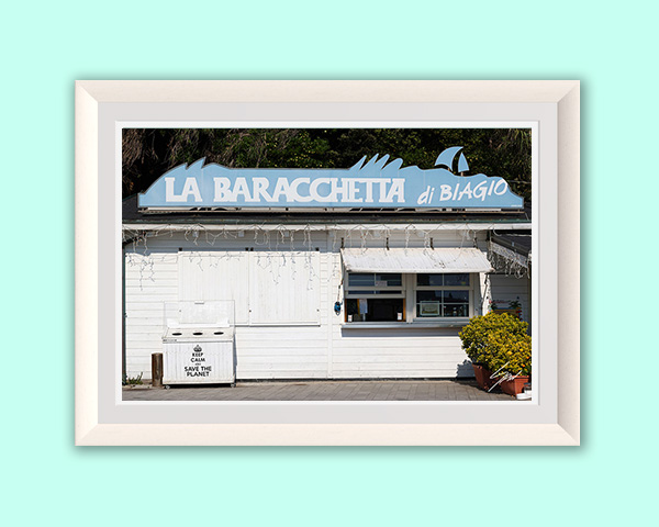 Historic white beach kiosk with the blue "La Baracchetta di Biagio" sign, photographed on the Ligurian coast in Italy.