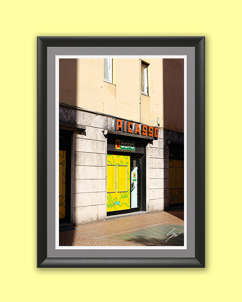 Fine art travel photography wall print capturing the colorful Picasso storefront on a quiet Italian street, blending everyday life with graphic design.