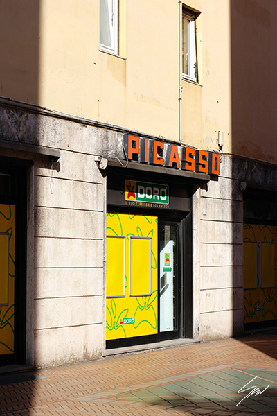 Fine art travel photography wall print capturing the colorful Picasso storefront on a quiet Italian street, blending everyday life with graphic design.