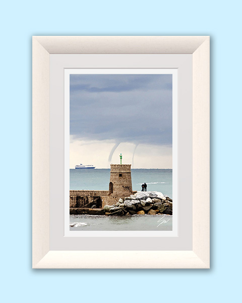 Historic stone tower at Recco harbor with twin waterspouts forming over the Ligurian Sea as a ferry passes in the distance.