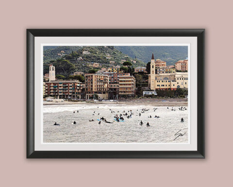 Fine art photograph of dozens of surfers gathered in the lineup with the colorful waterfront of Recco, Italy, in the background.