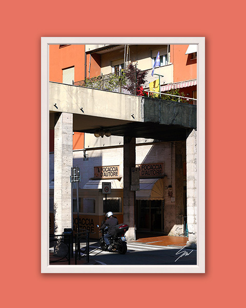 Fine art photograph of a scooter passing the famous Focaccia d'Autore bakery in Recco, Italy.