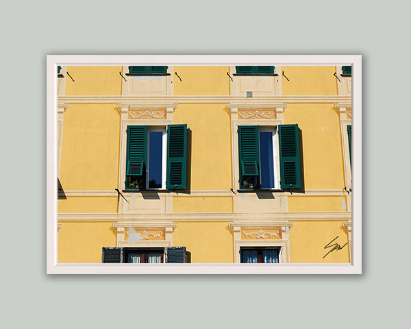 Fine art photograph of a classic Italian building featuring symmetrical green shutters against a vibrant yellow façade.